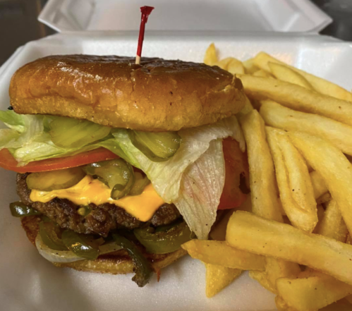 A juicy cheeseburger with lettuce, tomato, pickles, and onions, served with a side of golden French fries.