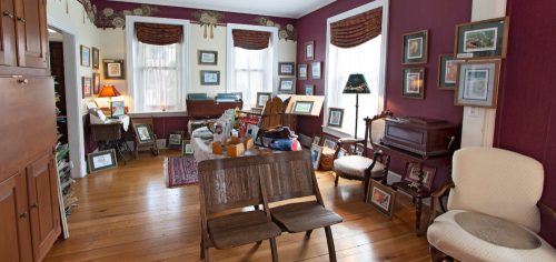 A cozy room with wooden floors, framed pictures on the walls, and vintage furniture, creating a warm, inviting atmosphere.