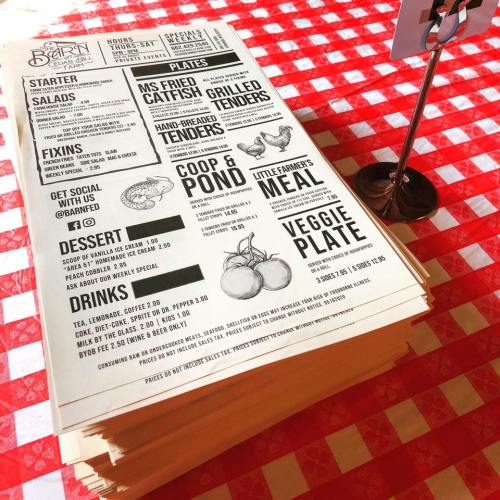 A menu on a red and white checkered tablecloth, featuring various food items and prices.