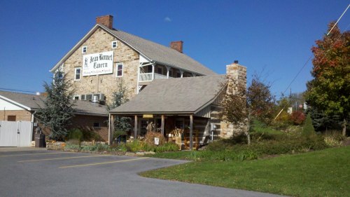 A stone building with a sign reading "Penn Haven Tavern," surrounded by greenery and a clear blue sky.