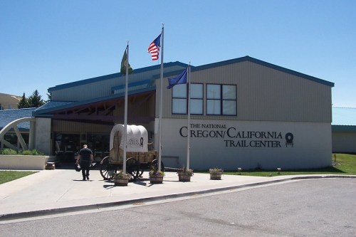 Exterior of the National Oregon-California Trail Center, featuring flags and a covered wagon in front.