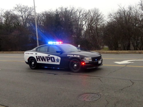 A police car with flashing lights parked on the side of a road, surrounded by trees in the background.