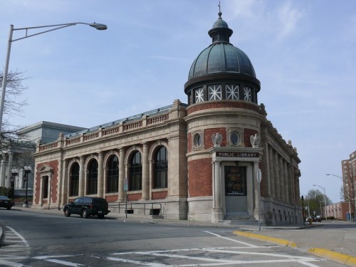 Historic public library building with a domed roof and large windows, set on a street corner.