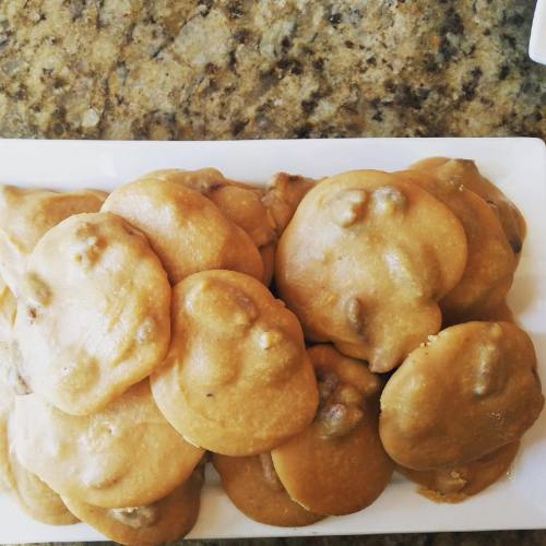 A plate of golden-brown cookies with a soft, rounded shape, arranged neatly on a granite countertop.