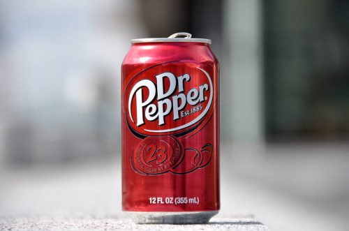 A can of Dr Pepper soda, red with white lettering, displaying "23 flavors" and "12 FL OZ" on the label.