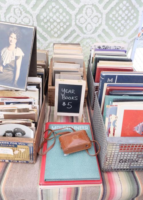 A display of vintage yearbooks and photographs, with a small sign reading "YEAR BOOKS $5" and a camera on top.