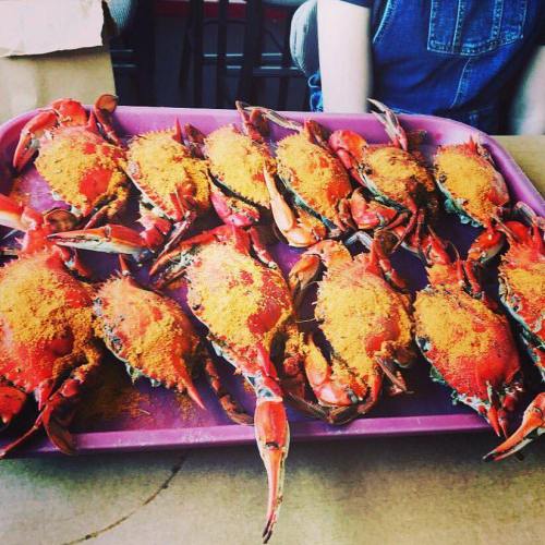 A tray of cooked crabs topped with a golden seasoning, arranged neatly on a purple tray.