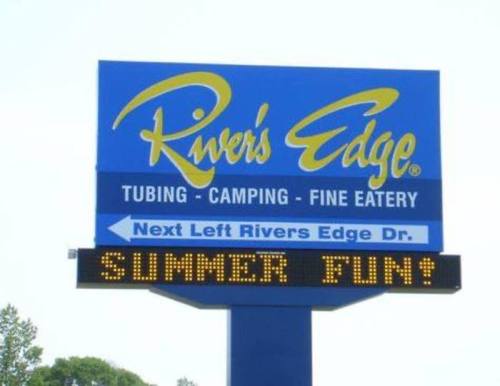 Sign for River's Edge featuring tubing, camping, and fine eatery with "SUMMER FUN!" displayed prominently.