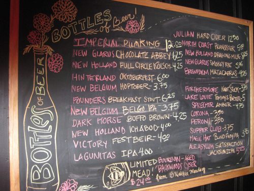 Chalkboard menu listing various beers with prices, including Imperial Plunking, New Glarus, and Founders Brewery options.