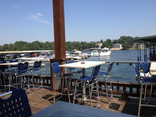 A waterfront view from a restaurant deck, featuring boats docked and a clear blue sky.