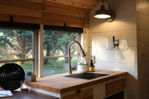 Bright kitchen with wooden accents, a modern sink, and large windows showcasing greenery outside.
