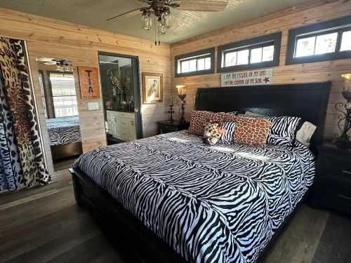 Cozy bedroom with zebra-striped bedding, wooden walls, and decorative accents, featuring a plush toy on the bed.