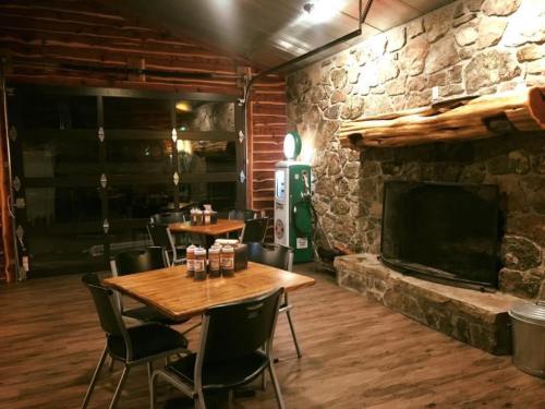 Cozy interior of a rustic restaurant featuring stone fireplace, wooden decor, and tables set for dining.