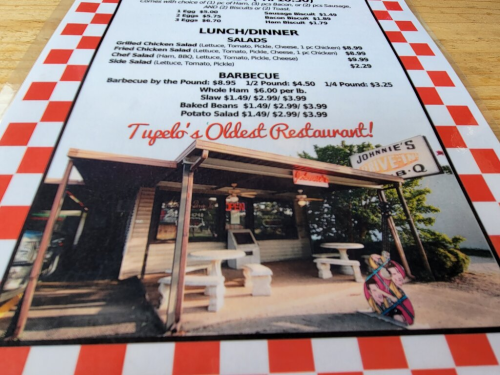 Menu featuring lunch and dinner options, including salads and barbecue, with a sign for Johnnie's BBQ, "Tupelo's Oldest Restaurant."