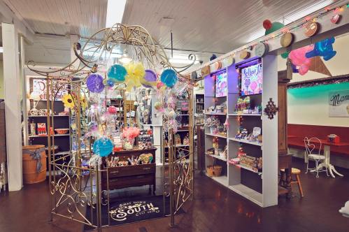 A colorful candy shop interior featuring a decorative display, shelves of sweets, and festive decorations.