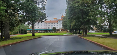 A view of a large, historic hotel surrounded by trees, with a cloudy sky overhead.