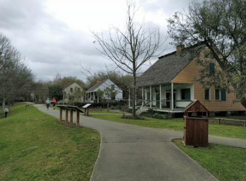A pathway in a park with historic houses, trees, and visitors walking on a cloudy day.