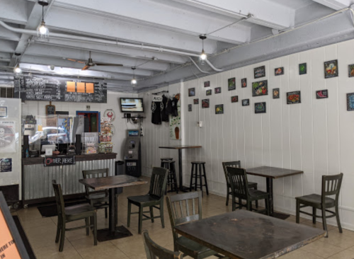 Interior of a casual eatery with wooden tables, chairs, and colorful wall art. Bright and inviting atmosphere.