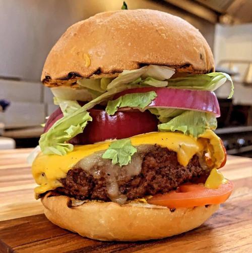 A juicy cheeseburger with lettuce, tomato, onion, and pickles, served on a toasted bun.