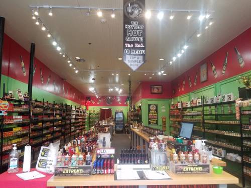 Interior of a vibrant hot sauce store, featuring shelves lined with various sauces and a sampling station.