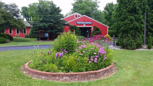 A vibrant flower garden in front of a red visitor center surrounded by greenery and trees.