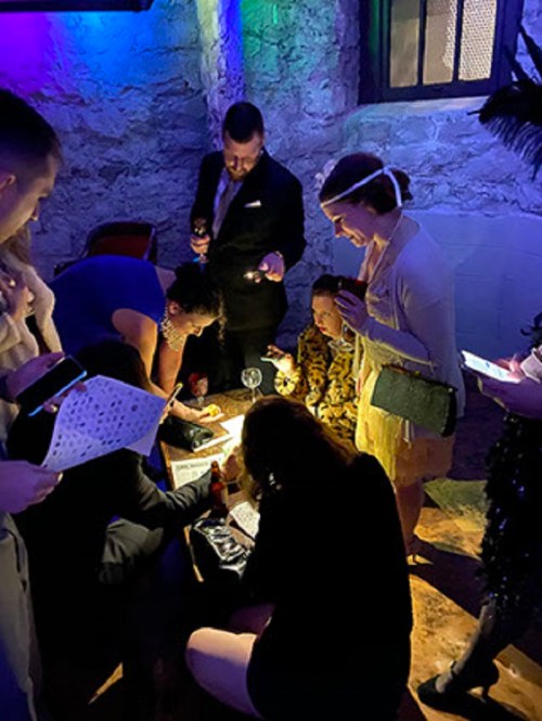 A group of people gathered around a table in a dimly lit room, engaged in conversation and activities.