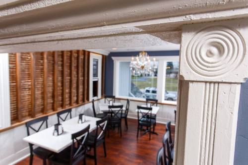A cozy restaurant interior featuring wooden accents, tables, and a chandelier, viewed through a decorative frame.