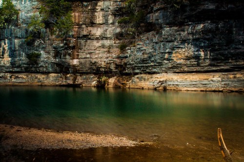 A serene body of water surrounded by rocky cliffs and lush greenery, reflecting the calm atmosphere of nature.