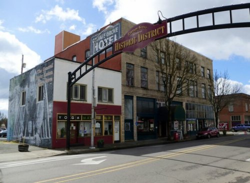 Historic district entrance with buildings, a mural, and shops, under a cloudy sky.