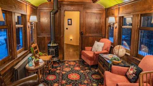 Cozy interior of a vintage train car, featuring wooden walls, plush seating, and a decorative rug.