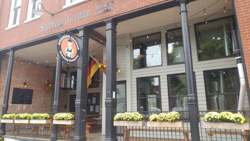Exterior of Stubborn German Brewing Company, featuring a brick facade, outdoor seating, and colorful flower boxes.