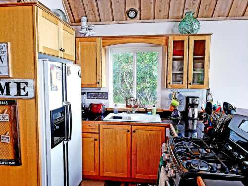 Bright kitchen with wooden cabinets, a window, and modern appliances, featuring a sink and a gas stove.