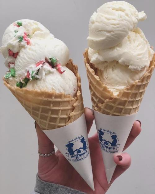 Two ice cream cones held in a hand: one with green and red sprinkles, the other plain vanilla.