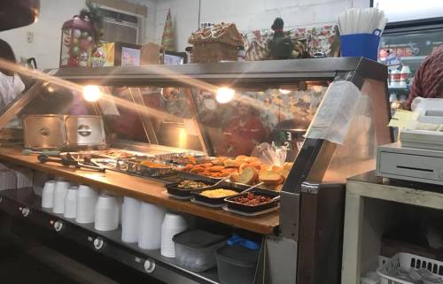 A food counter displaying various dishes, with warm lighting and festive decorations in the background.