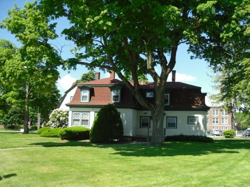 A charming two-story house surrounded by lush green trees and a well-maintained lawn on a sunny day.
