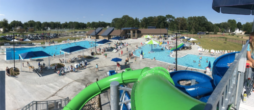 Aerial view of a busy water park with pools, slides, and people enjoying a sunny day.