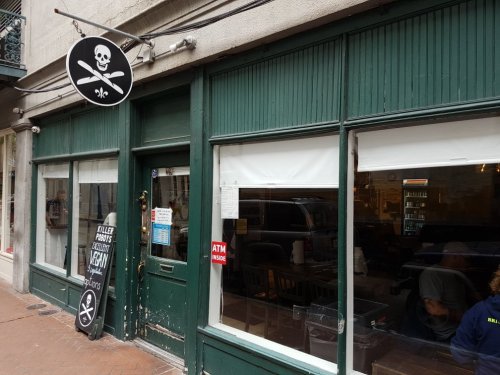 Exterior of a restaurant with a pirate-themed sign, featuring green wooden panels and large windows.
