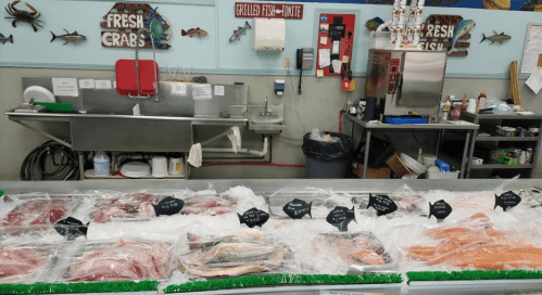A seafood market display featuring various fresh fish and seafood on ice, with labels for each type.