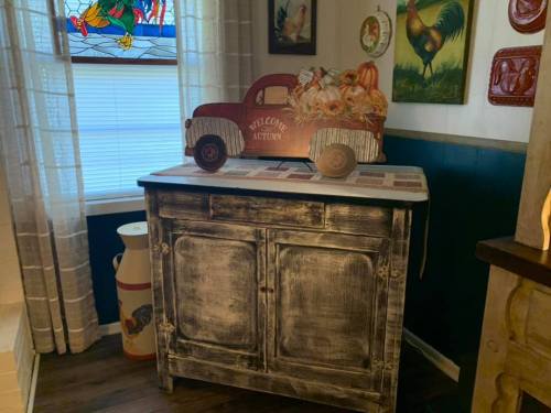 A rustic wooden cabinet with a vintage red truck decoration, filled with autumn-themed items, in a cozy room.