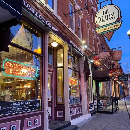 A charming ice cream parlor with neon signs for chocolates and homemade ice cream, set in a historic building.