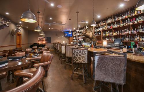 A cozy restaurant interior featuring a bar with shelves of liquor, wooden tables, and rustic decor with antler accents.