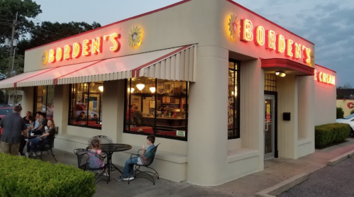 A brightly lit ice cream shop named "Bordent's" with outdoor seating and customers enjoying their treats.