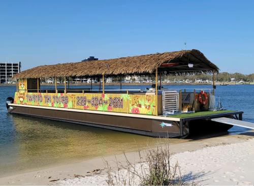 A colorful boat with a thatched roof docked by the shore, surrounded by water and blue skies.