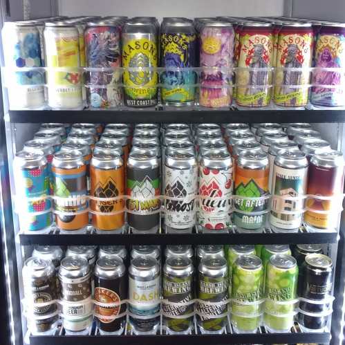 A display of various colorful beer cans arranged on shelves, showcasing different brands and designs.