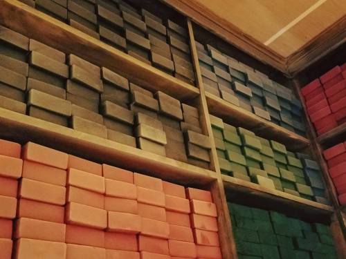 Shelves filled with neatly stacked colorful blocks in shades of gray, green, and orange.