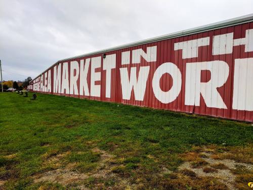 A large red building with white letters reading "THE BEST MARKET IN THE WORLD" on its side, surrounded by grass.