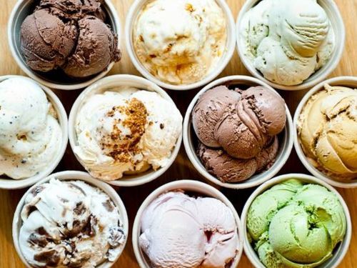 A variety of ice cream scoops in small cups, featuring flavors like chocolate, mint, and vanilla.