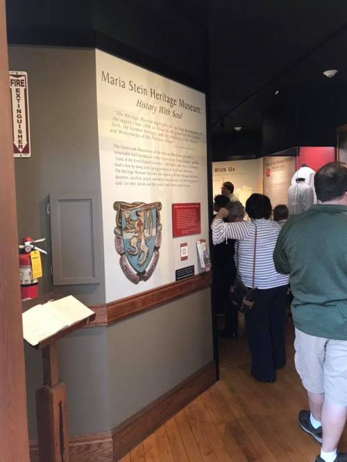 Interior of the Maria Stein Heritage Museum, featuring a historical display and visitors engaging with the exhibits.