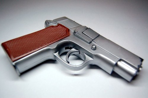 A silver toy pistol with a brown grip, positioned on a light background.