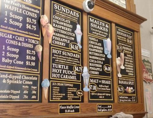Menu board featuring sundaes, malts, shakes, and ice cream cones with prices listed for each item.
